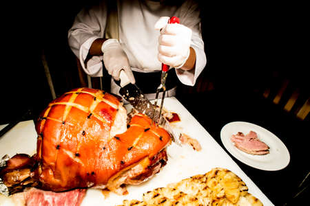 butcher's hand while fast cuts a piece of raw ham, cut hamの写真素材