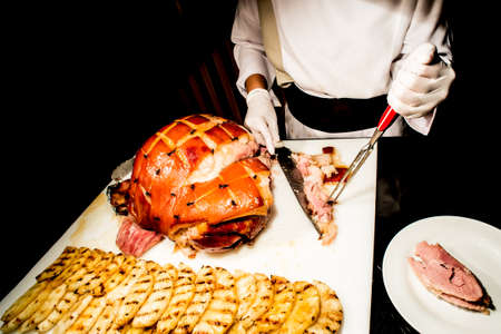 butcher's hand while fast cuts a piece of raw ham, cut hamの写真素材