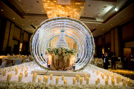Flowers and decorations around wedding cake with chandelier on ceiling in the grand ballroom luxury hotel.のeditorial素材