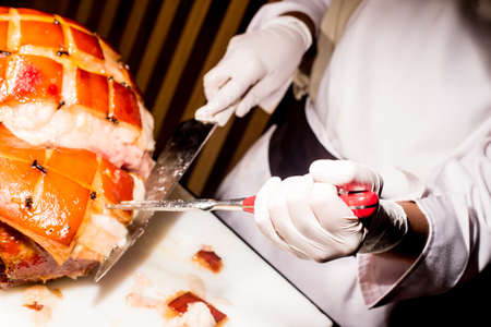 butcher's hand while fast cuts a piece of raw ham, cut hamの写真素材