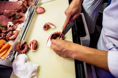 Cutting the salmon with a knife,Japanese chef making sashimi in kitchen,Sushi are madeの写真素材