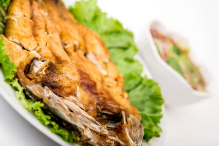 Fried snapper with chili sauce in blue dish against bamboo background,Fried snapper fishの写真素材