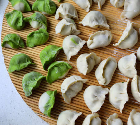 Green and white raw Chinese dumplings(Jiaozi) on natural sorghum stalk pad. Jiaozi is a traditional food for Chinese in many festivals.の写真素材