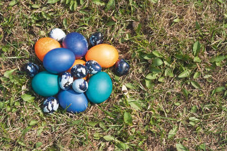 Some colored Easter eggs on the lawn. Chicken and quail eggs, painted for the celebration. Top view,...