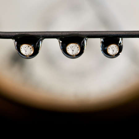 Three water droplets displaying an old pocket watch within each droplet!の写真素材
