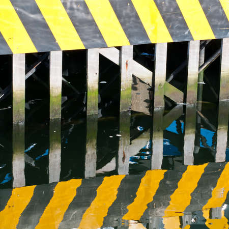 The hazard warning on the lock gate at the marina, along with its reflection.の写真素材