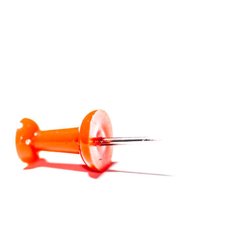 A macro shot of a single red push pin isolated against a white background の写真素材