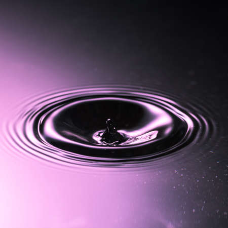 Ripples spread out from a water drop falling into some water の写真素材