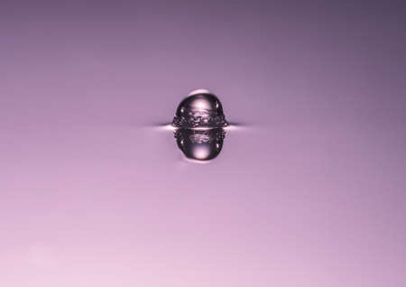 A macro shot of a water drop impacting on the surface of some water の写真素材