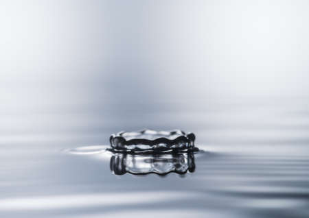 A macro shot of a small water crown and its reflection の写真素材