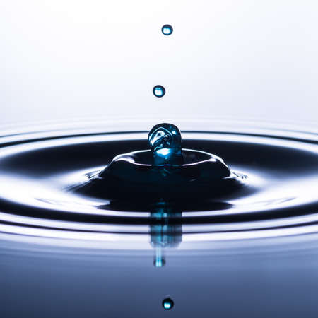 An abstract macro shot of water drops falling into a pool of water