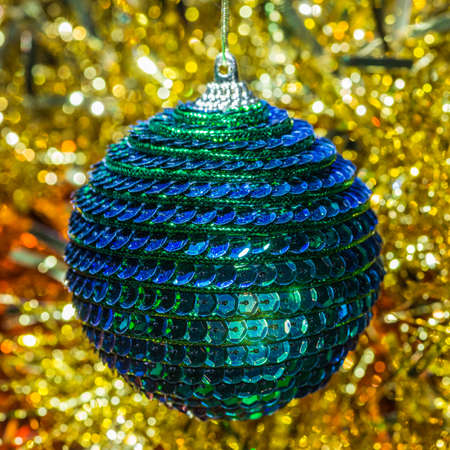 A macro shot of a green Christmas bauble shot against some tinsel.