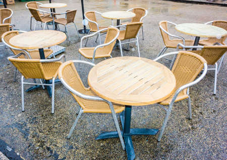 Empty tables and chairs outside a coffee shop on a rainy day.の写真素材