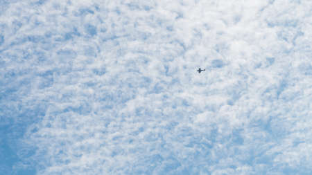 A shot of a WWII Spitfire flying through a blue sky, peppered with fluffy white clouds.の写真素材
