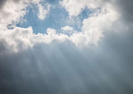Rays of light shine through the dark surrounding clouds.の写真素材