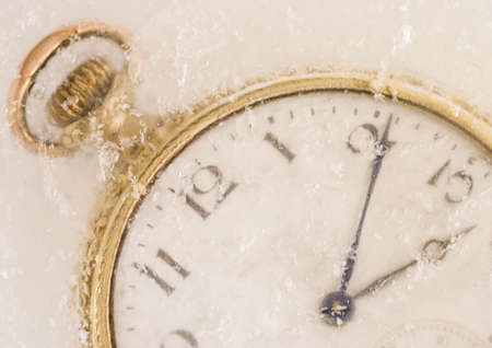 A macro shot of an old pocket watch covered in ice.
