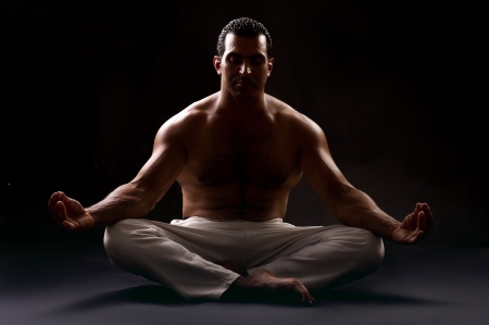 Bare chested guy Practicing yoga in low key shot の写真素材