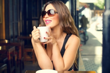 Beautiful young woman having coffee outdoors  の写真素材