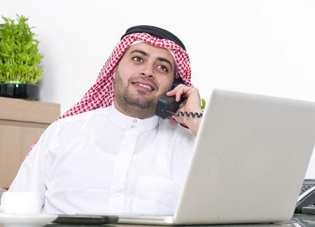 Arabian Businessman using Laptop and talking on phoneの写真素材