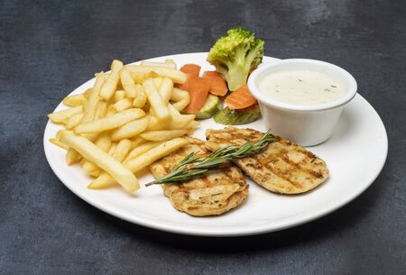 plate of grilled chicken with vegetables on dark backgroundの写真素材