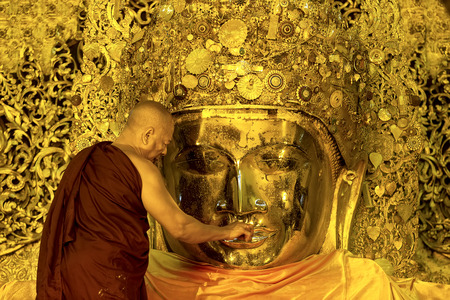 MANDALAY-JAN 25 The senior monk put wax on Buddha image lips  in ritual of face wash to Mahamuni Buddha image on JAN 25,2013 at Mahamuni temple-Mandalay Myanmar のeditorial素材