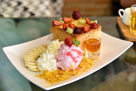 closup of Honey toast with strawberry ice cream and honey syrup, rasberry and strawberry on top.