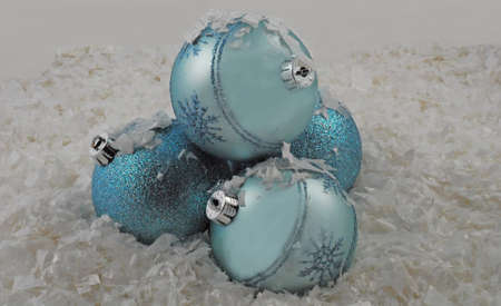 trio of blue christmas ornaments in snowの写真素材