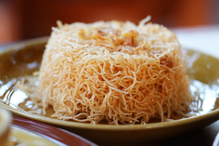 crispy Thai rice noodles with Sweet and Sour sauce in brown ceramic plate, Thai people called "Mee Krob"の写真素材