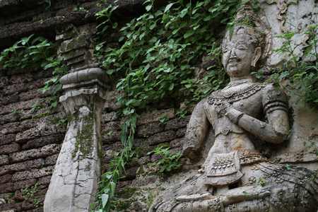400 years old ruined ancient standing and praying of male angel statue at Chiangmai, Thailand,...