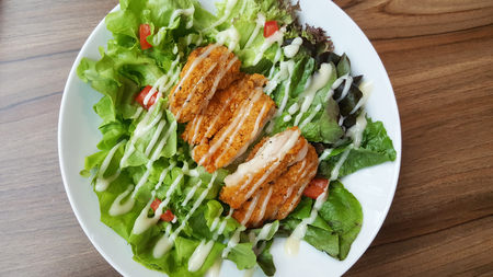 Breaded fried chicken with organic green caesar salad tomato on wooden table at western restaurant, food recipe menu advertisementの写真素材