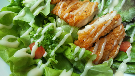 Breaded fried chicken with organic green caesar salad tomato on wooden table at western restaurant, food recipe menu advertisementの写真素材