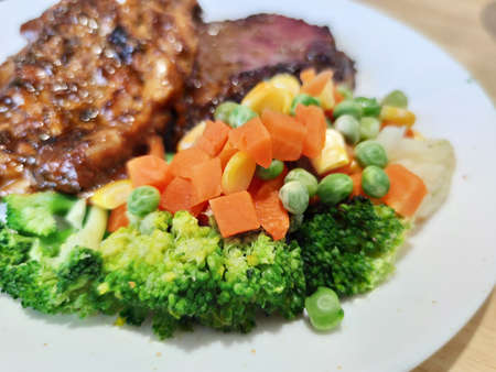 various colorful vegetables dressing corn carrot peas lemon serving on white plate serving with Sliced Grilled organic pork, beef Ribeye steak decorated, One famous menu of secret recipe from street fの写真素材