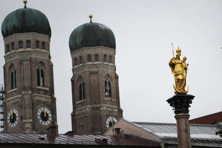 Golden scuplture of Virgin Mary at  Marienplatz with Both onion domes of the Gothic cathedral backgrounds, Munich, Germany, Travel Destinationsの写真素材