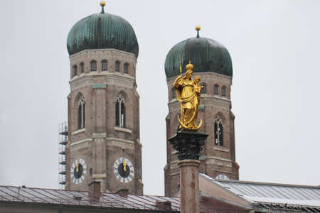 Golden scuplture of Virgin Mary at  Marienplatz with Both onion domes of the Gothic cathedral backgrounds, Munich, Germany, Travel Destinationsの写真素材