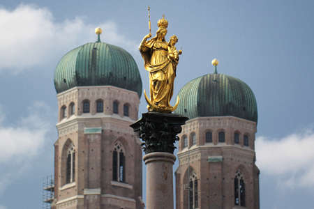 Golden scuplture of Virgin Mary at  Marienplatz with Both onion domes of the Gothic cathedral backgrounds, Munich, Germany, Travel Destinationsの写真素材