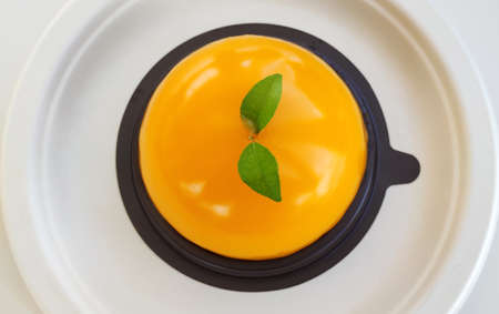 a piece of jelly orange cake with green leaf serving on black plastic tray and recycled plate at coffee gourmet cafe, graphic design component, rough texture backgroundsの写真素材