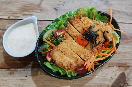 Breaded fried chicken with organic colorful salad and serving with caesar sauce on wooden table at western restaurant, food recipe menu advertisementの写真素材