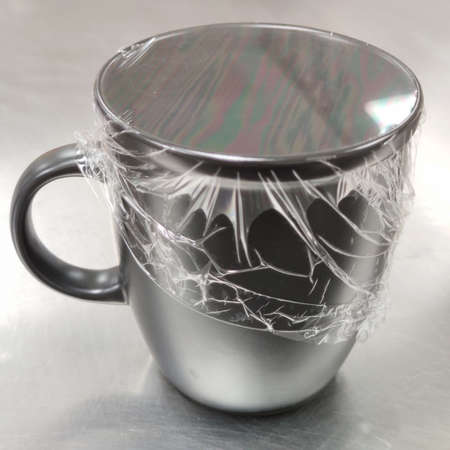 Steel mug wrapped with plastic film isolated on white background, unfinished drink beverage, temperature keeping packaging cupの写真素材