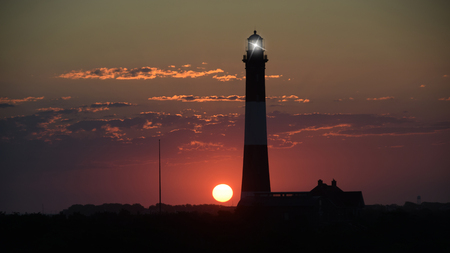 A Sunrise one Summer Morning by the Shore with a Lighthouseの写真素材