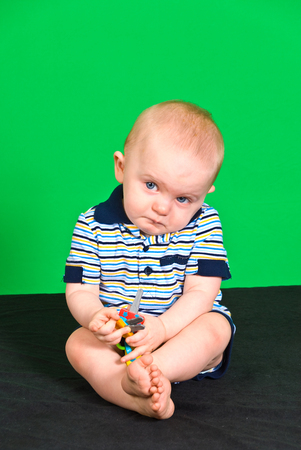 Sad 10 Month old Baby Boy on Green Screen playing with toyの写真素材