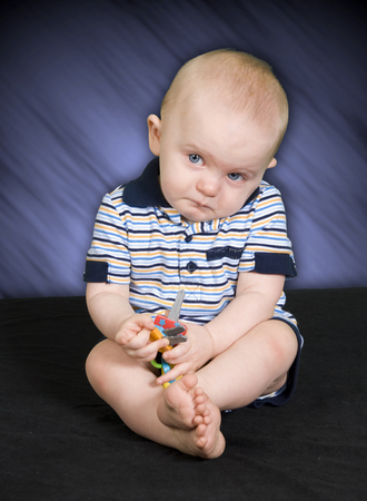 Sad 10 Month old Baby Boy playing with toyの写真素材