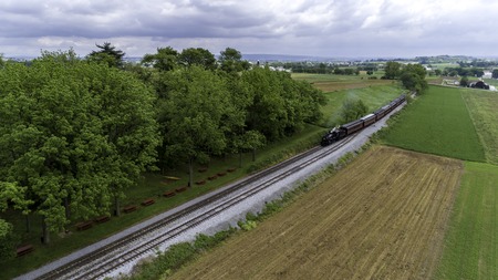 Aerial View of a Steam Passenger Train Puffing Smoke in Amish Countryside on a Sunny Spring Dayの写真素材