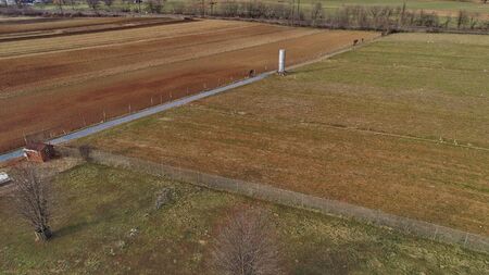 Aerial View of Amish Farm Worker Turning the Field in Early Spring as Seen by a Droneの写真素材