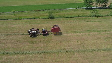Aerial View of an Amish Farmer Harvesting His Crop with 4 Horses and Modern Equipmentの写真素材