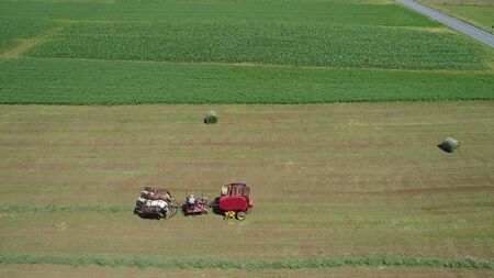 Aerial View of an Amish Farmer Harvesting His Crop with 4 Horses and Modern Equipmentの写真素材