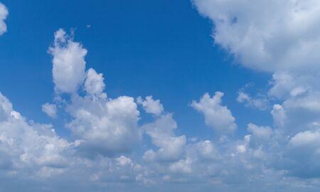 White Fluffy Clouds Floating in the Bright Blue Skies on a Summer Dayの写真素材