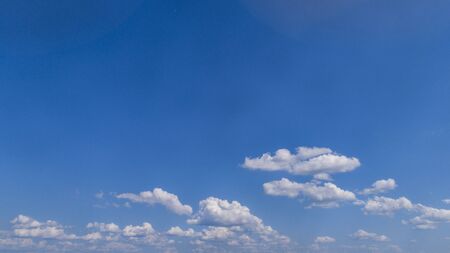 White Fluffy Clouds Floating in the Bright Blue Skies on a Summer Dayの写真素材