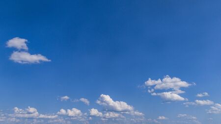 White Fluffy Clouds Floating in the Bright Blue Skies on a Summer Dayの写真素材