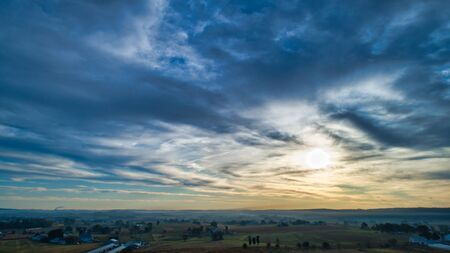 Aerial View of a Late Afternoon Sun With Partly Cloudy Blue Sky Over Farm Countryside Background
