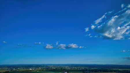 Blue sky and multiple clouds background showing a horizonの写真素材